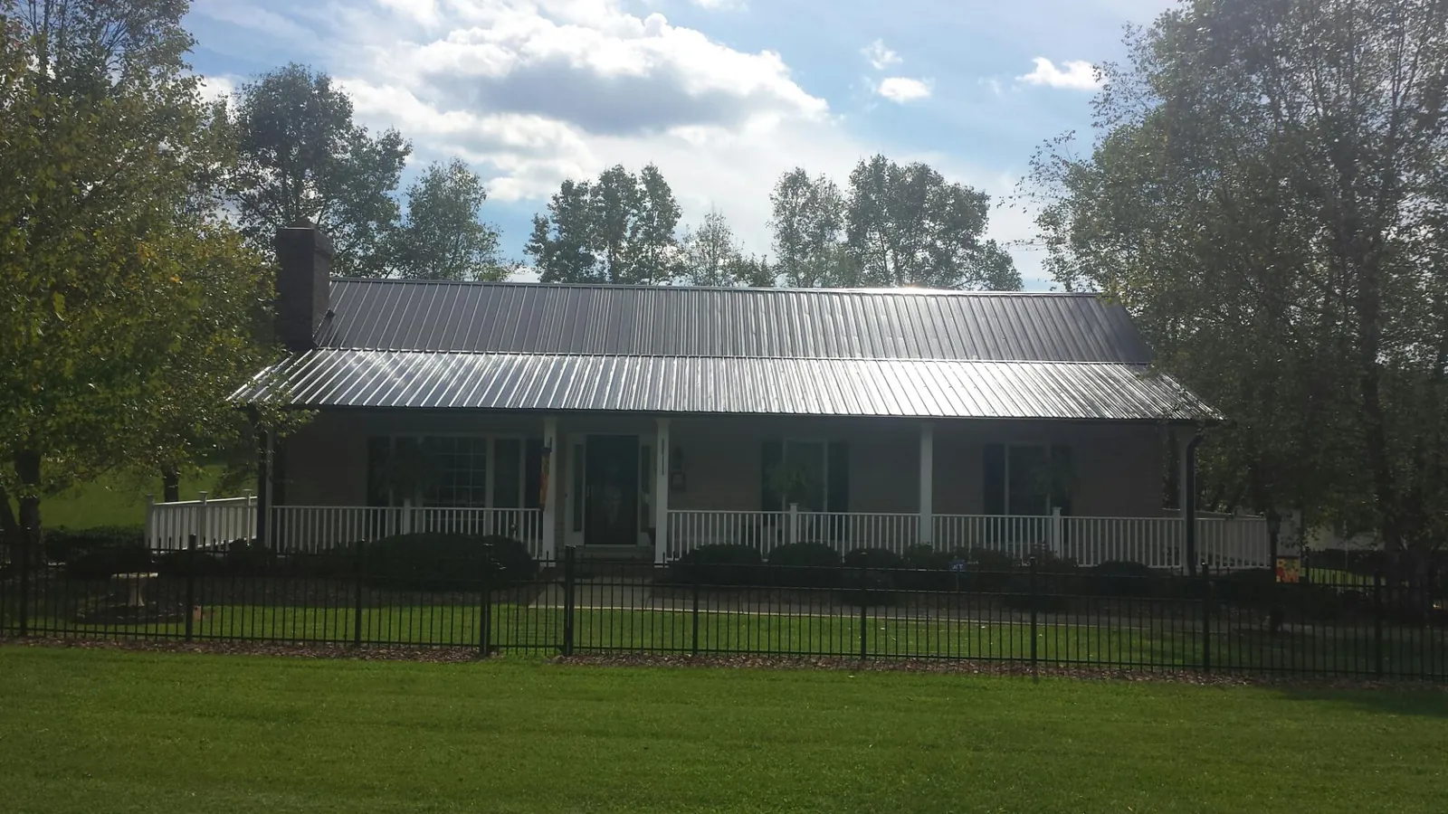 Gray metal roof on a brick ranch with a full width front porch — Gutter Guard Installation work by our crew in Nicholson